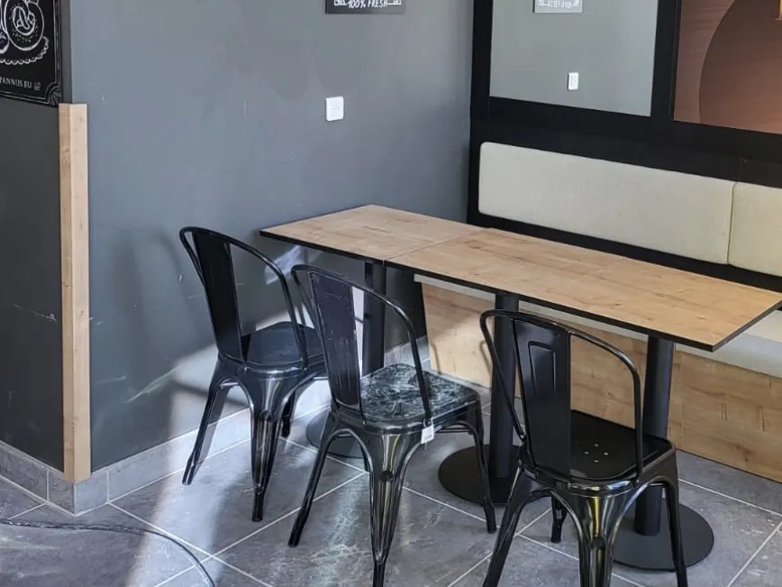 Zona de mesas con bancada tapizada y estantes circulares de madera en la cafetería Pannus