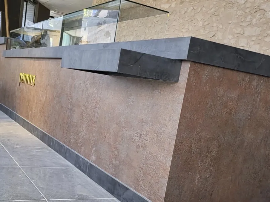 Detalle del mostrador con encimera oscura y frente efecto óxido en la panadería Pannus