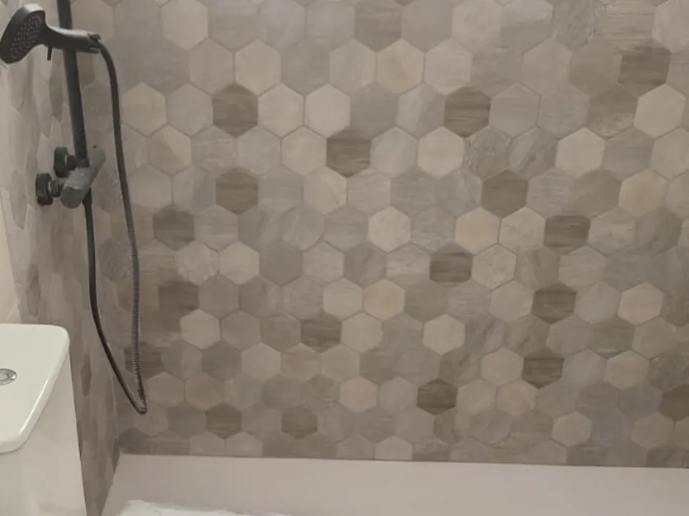 Baño con alicatado de mosaico hexagonal y plato de ducha de obra